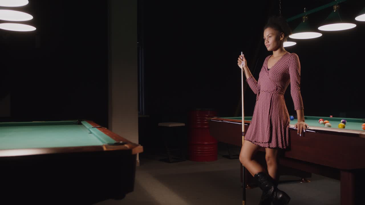 mujer jugando al billar en un club nocturno oscuro