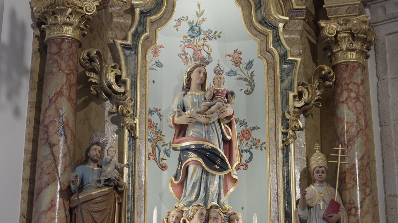 Detail of religious sculptures and marble columns with gold leaf ornamentation in a historic chapel.