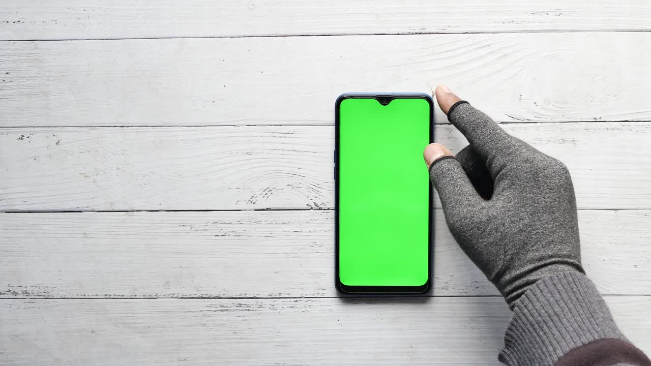 Smartphone con schermo verde su tavolo di legno