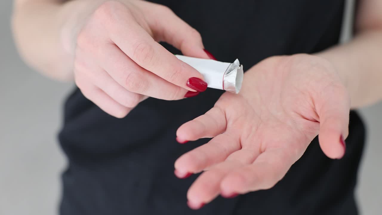 Person dispensing chewing gum from a wrapper into their hand