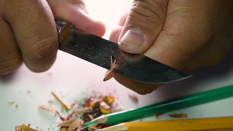 Footage-of-hands-slowly-sharpening-a-pencil-and-some-coloured-pencils-with-a-sharp-knife