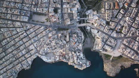 top down aerial timelapse of the town of polignano a mare during the morning as traffic moves across the roads