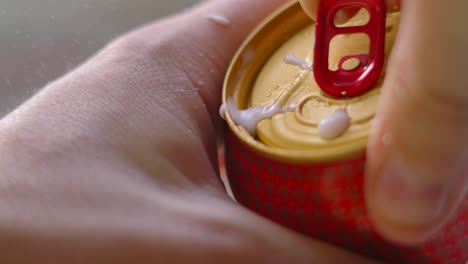 beer can being opened in slow motion with small spray coming from top. fresh lager popped with hands