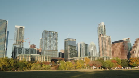 Edificios-Del-Horizonte-De-La-Ciudad-Del-Centro-De-Austin,-Texas,-Al-Atardecer-Con-El-Parque-Auditorium-Shores-En-Primer-Plano