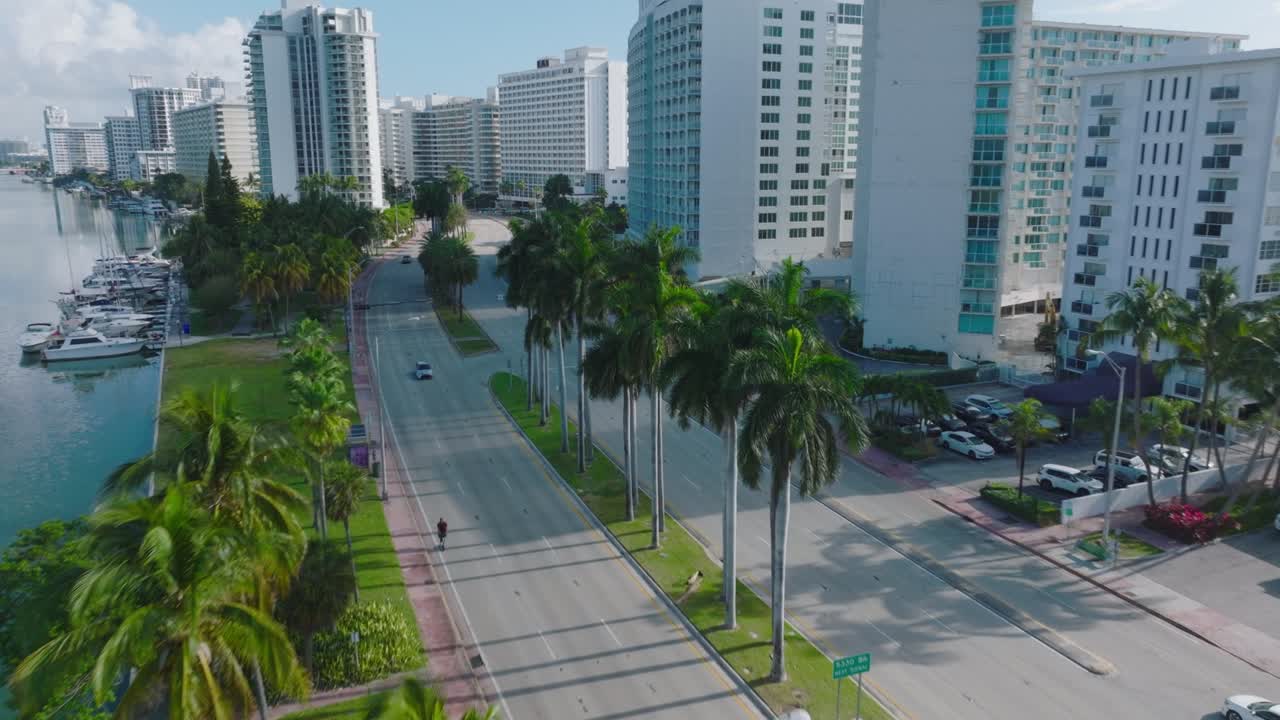 barrio lujoso moderno en una zona tropical. coches conduciendo en una carretera de varios carriles que conduce entre edificios de apartamentos de gran altura. miami, ee.uu.
