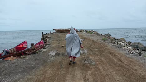 person walking along a pier on a cloudy, windy day