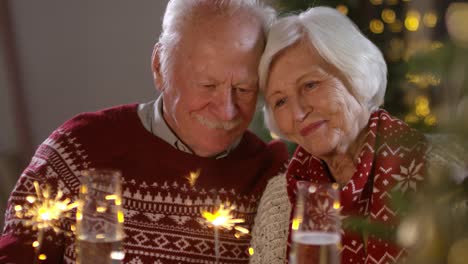 loving senior couple celebrating christmas holidays with sparklers fireworks at home