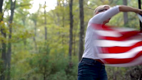 pretty blonde woman throws the american flag over her head and in front of her and then back in a wave