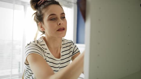 Tilt-up-video-of-young-woman-renovating-old-furniture.