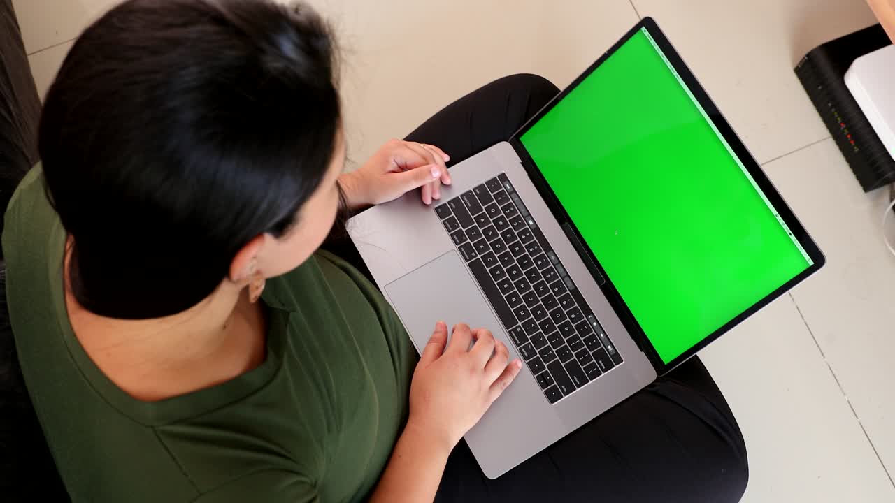 Top view of woman using laptop computer with green screen