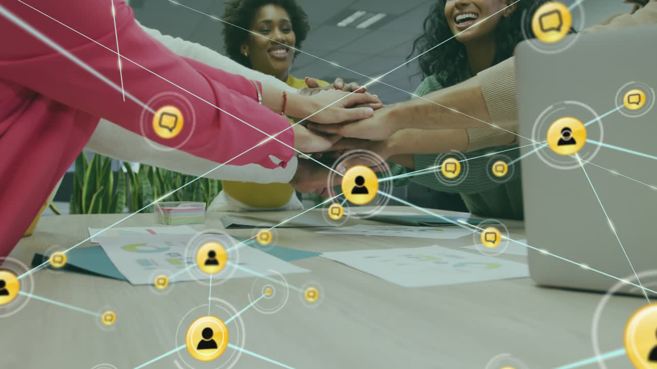 Animation of connected icons over diverse female coworkers stacking hands in office