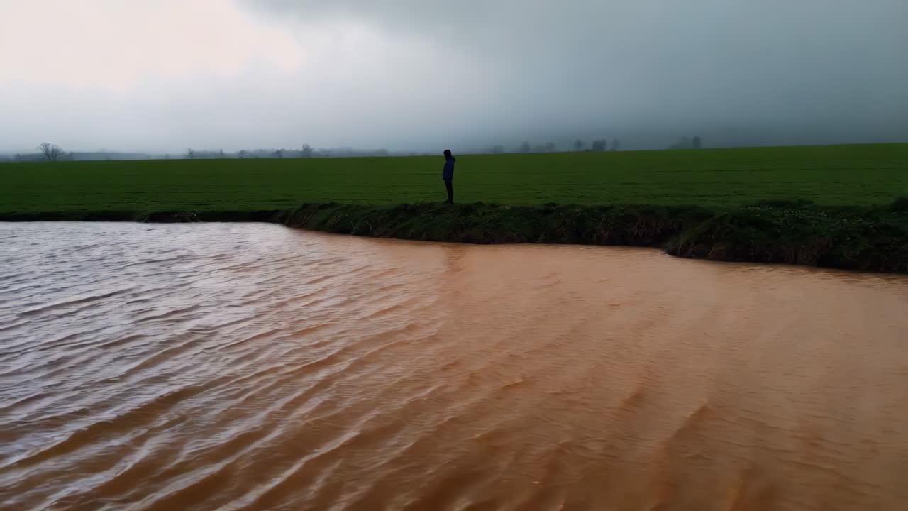 Person standing by a flooded field