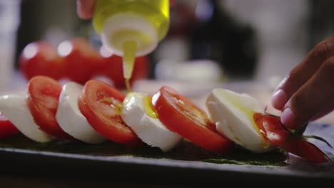 Pouring-olive-oil-onto-tomatoes-and-cheese