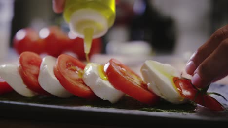 pouring olive oil onto tomatoes and cheese