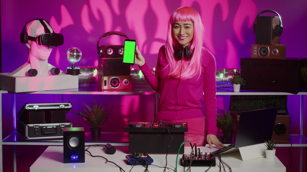 Woman with Pink Hair Showing Smartphone with Green Screen in DJ Setting