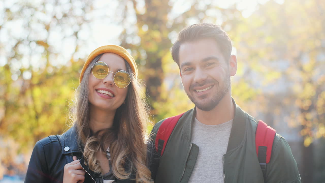 Young Caucasian woman wearing glasses and beanie and caucasian man looking aside