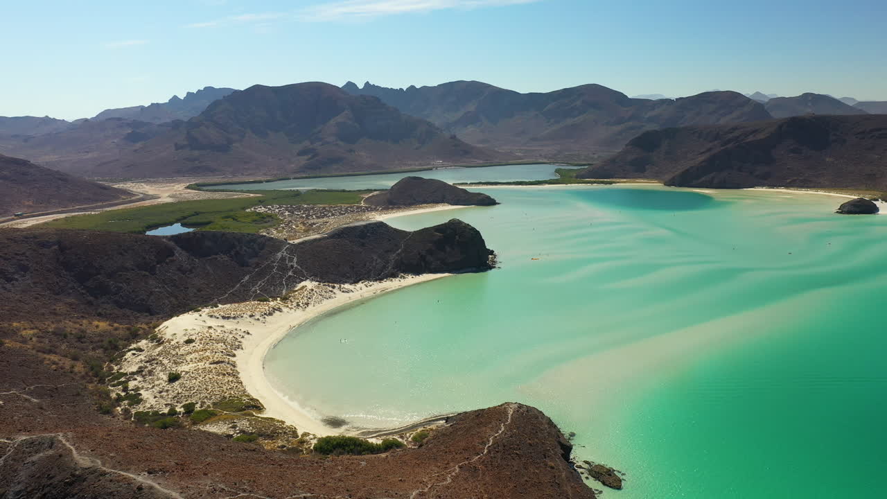 붉은 언덕, 청록색 바다, 백사장과 산을 지나는 발란드라 해변의 시네마틱 드론 샷
