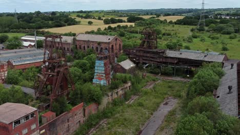 abandonada vieja mina de carbón cubierta de maleza edificios de museos industriales vista aérea acercar lento