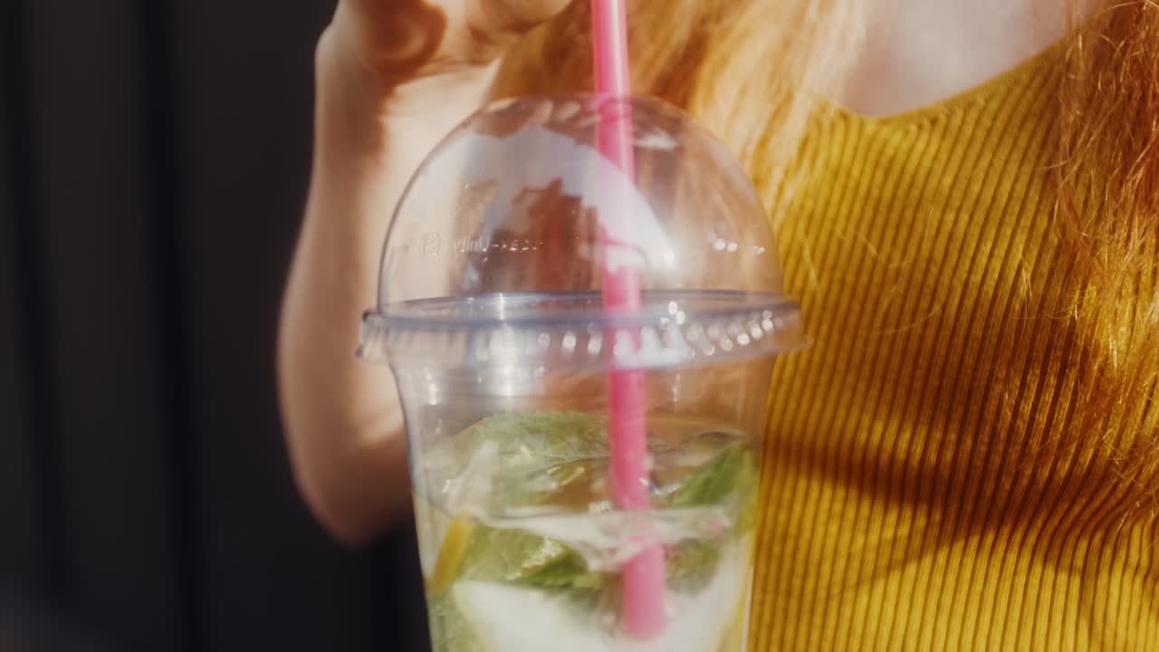 야외 에서 상쾌 한 레모네이드 를 마시고 있는 여자