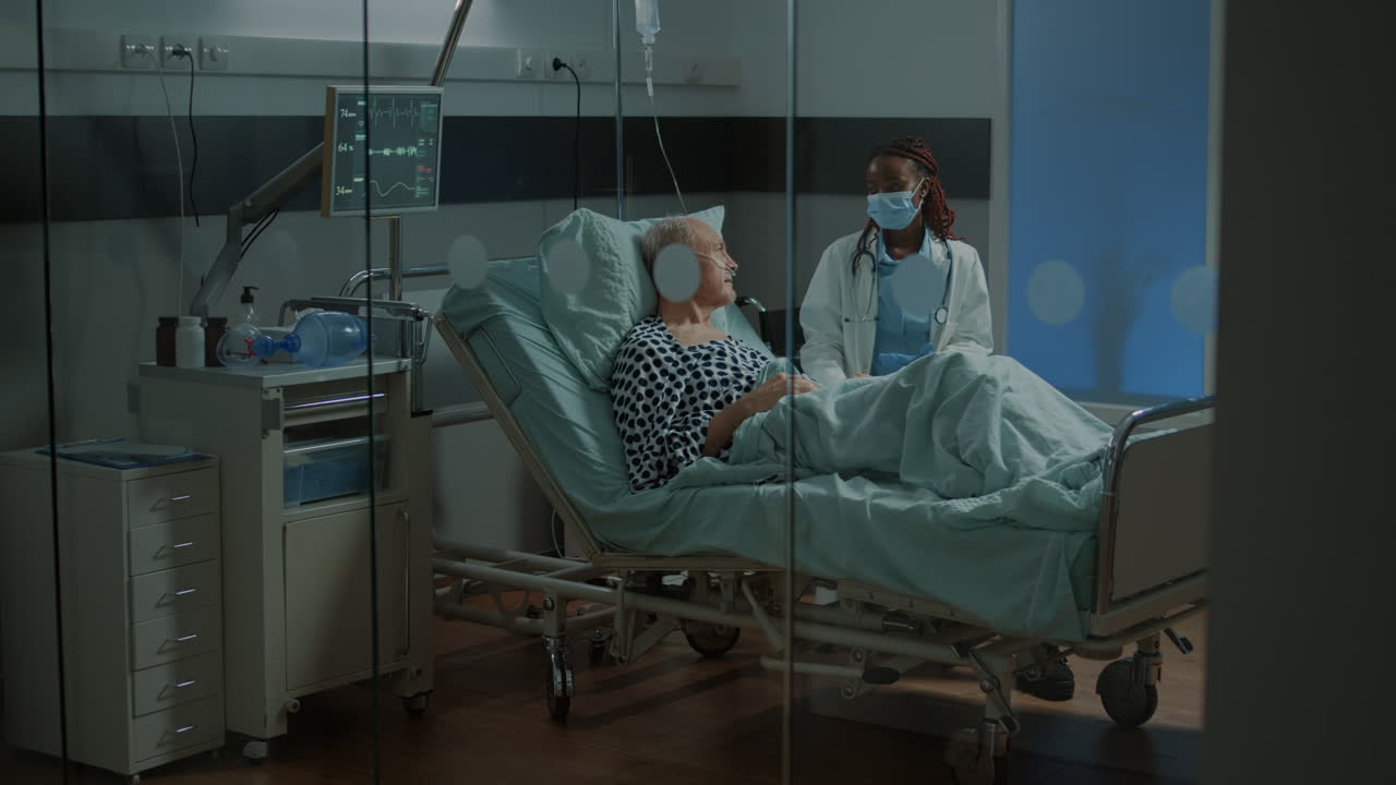 Old patient and african american doctor talking in hospital ward