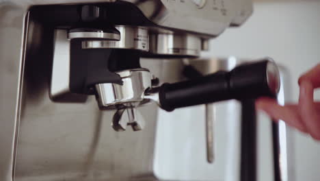 Young-male-grinding-coffee-ground-into-portafilter-at-home-for-espresso