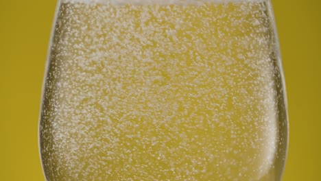 extreme close-up of a glas with sparkling water isolated on yellow background