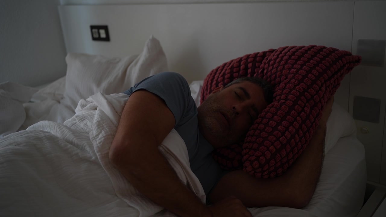 Un uomo riposa pacificamente mentre dorme comodamente e profondamente nel suo letto accogliente a casa.