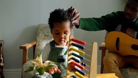 Front-view-of-cute-little-black-son-playing-with-abacus-in-living-room-of-comfortable-home-4k