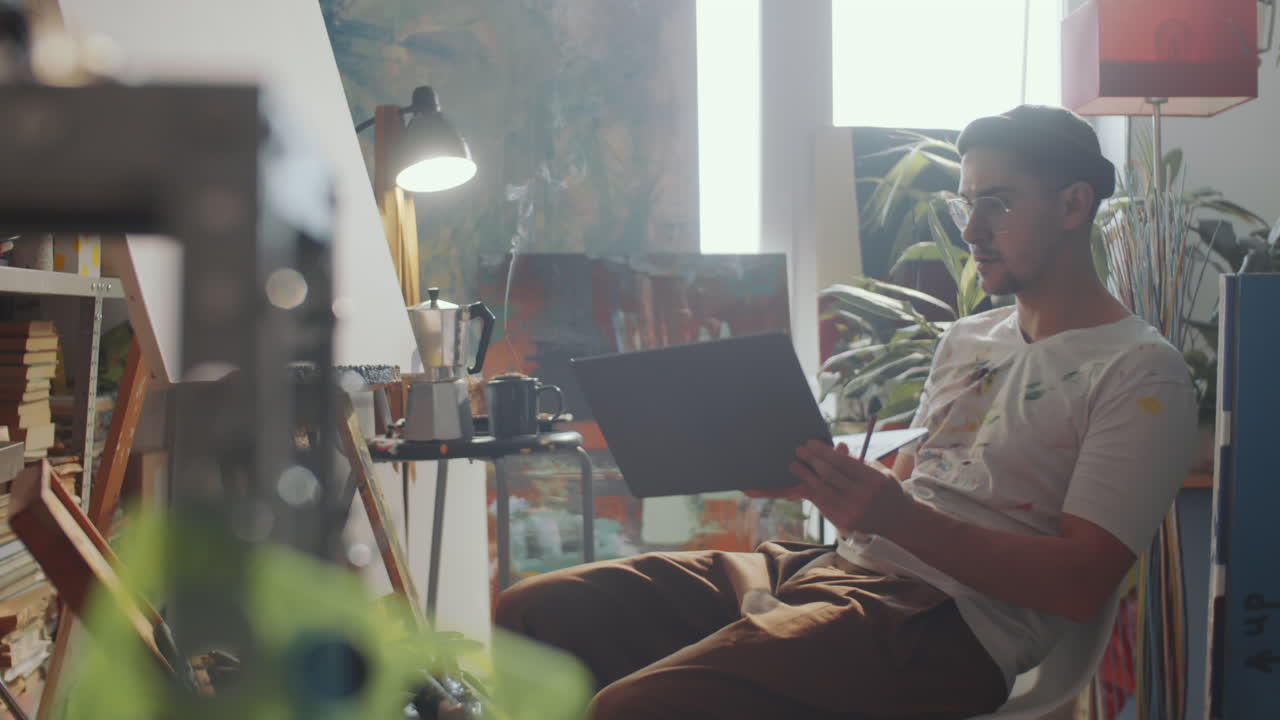 artista discutindo pintura na web chamada em laptop no estúdio