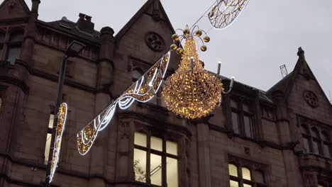 slow motion pan shot of christmas lights in manchester with ornate character building on dark day