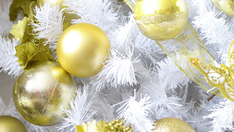 detalle de un árbol de navidad blanco adornado con objetos dorados.