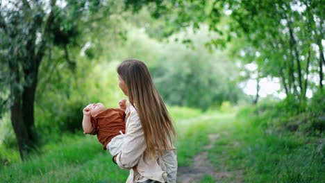 happy caucasian mother is waving her one-year-old baby boy outdoors. little cute child smiles to his mom.