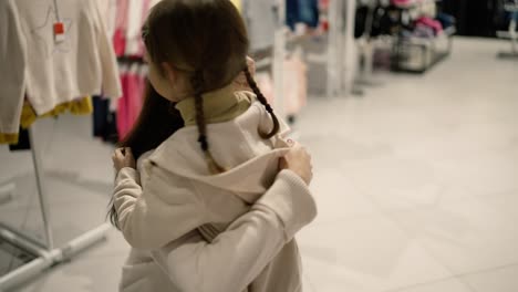 young beautiful mother hugs a little daughter in shopping mall