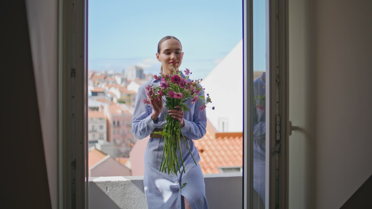 Romantic lady smelling bunch of wildflowers on terrace. Girl enjoying bouquet