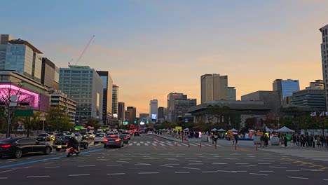 seoul city car traffic by gwanghwamun square at sunset, crowd of people sightseeing, majestic downtown skyscraper building against colorful sky