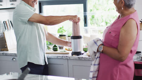 Feliz-Pareja-Birracial-Senior-Preparando-Bebidas-Saludables-En-La-Cocina