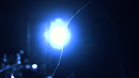 una figura encapuchada sale de la oscuridad y mira boquiabierta una sola fuente de luz que se derrama desde una ventana hacia una cocina en una noche oscura y fría