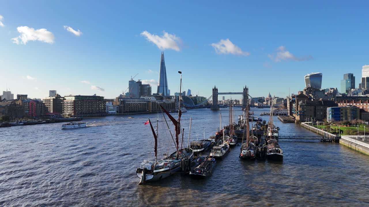 Old sailing barges moored on river Thames Tower bridge London UK in background Panning drone aerial