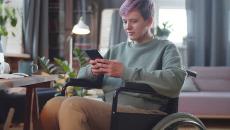 young woman in wheelchair using smartphone