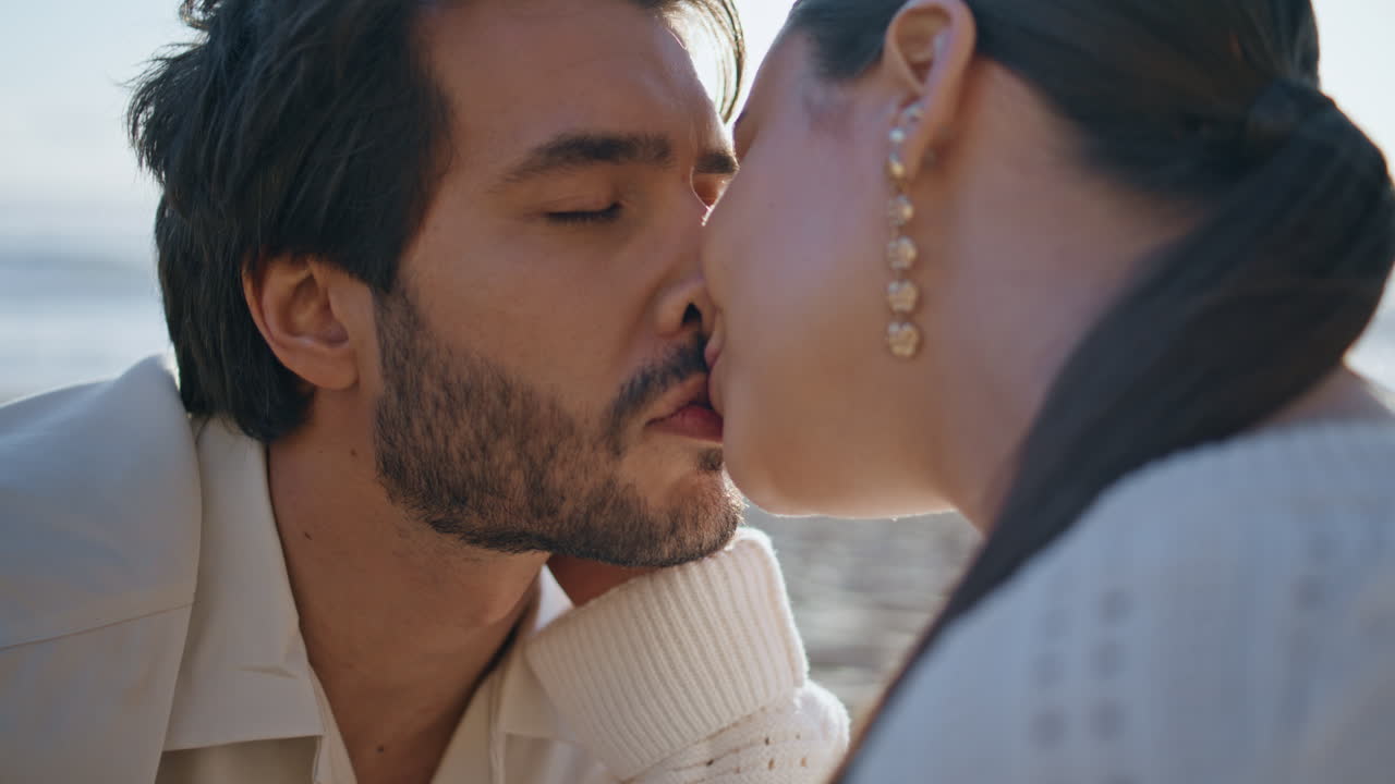 amanti affettuosi che si baciano in spiaggia guardando con amore da vicino. coppia sulla costa