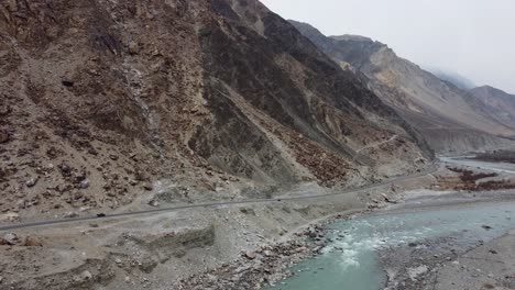 Aerial-drone-shot-of-KKH-road-along-picturesque-Karimabad-Hunza-Valley-with-Rakaposhi-mountains-in-the-background-in-Hunza,-Balochistan