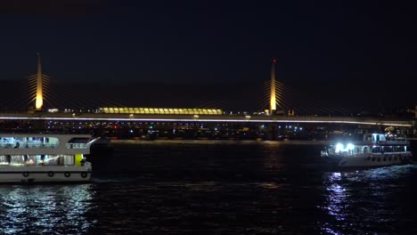 illuminated sightseeing boats on bosphorus strait in front of bridge in istanbul