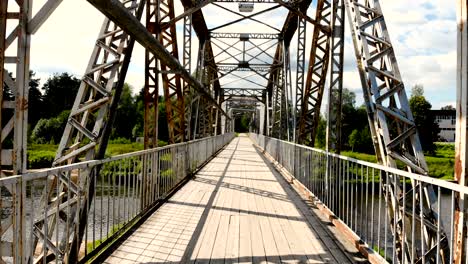 drone footage flying through metal bridge over river in valmiera, latvia