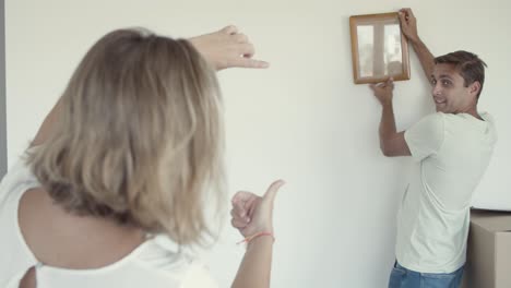 family couple and kid hanging picture frame on wall