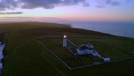 vista aérea del faro de la cabeza del bucle que brilla al amanecer contra un cálido cielo del crepúsculo
