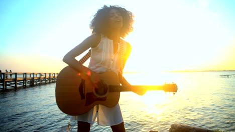 mujer afroamericana con cabello afro tocando la guitarra