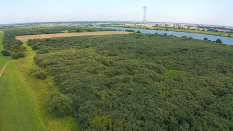 Vista-Aérea-Superior-De-Drones-Volando-Sobre-El-Río-De-Tierras-De-Cultivo-En-El-Fondo