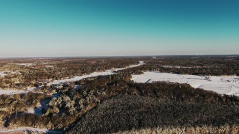 a stunning drone shot featuring a snow-dusted treeline in the foreground with a field and highway stretching across the snowy south georgia landscape.