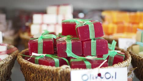 close-up of a basket of handmade red olive oil soap bars with green ribbons