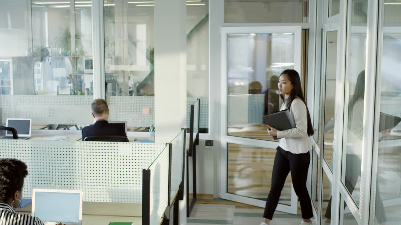 азиатская бизнес-леди проходит через современный офис в открытом пространстве